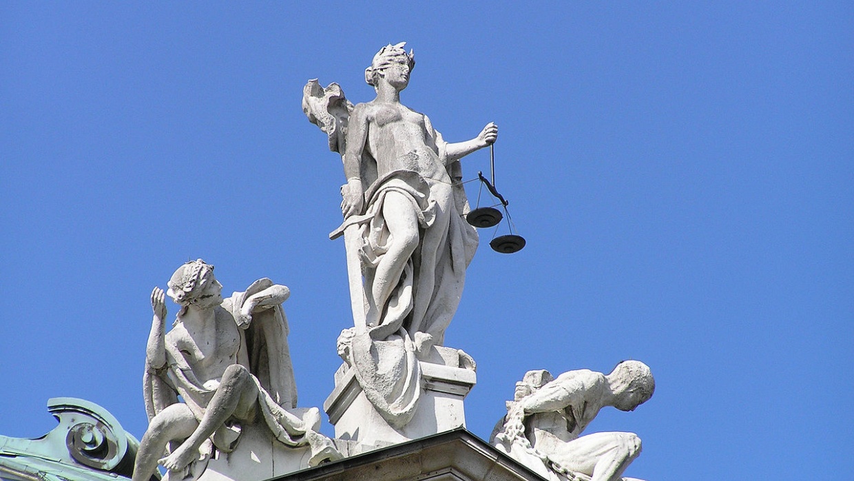 Statuengruppe „Gerechtigkeit“ von Balthasar Schmitt, bestehend aus Justitia mit Waage und Schwert, sowie Unschuld (links) und Laster (rechts), auf dem Südgiebel des Justizpalastes in München. Architekt: Friedrich von Thiersch. Fertiggestellt: 1897.
